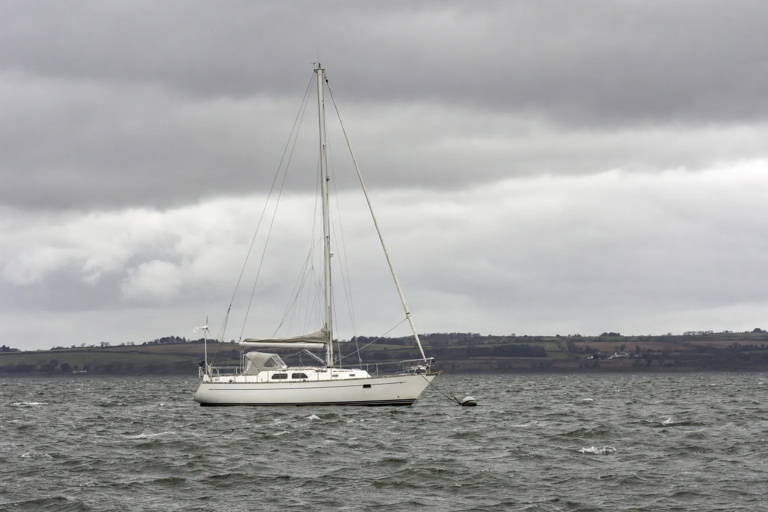 A yacht on a swinging mooring in grey weather